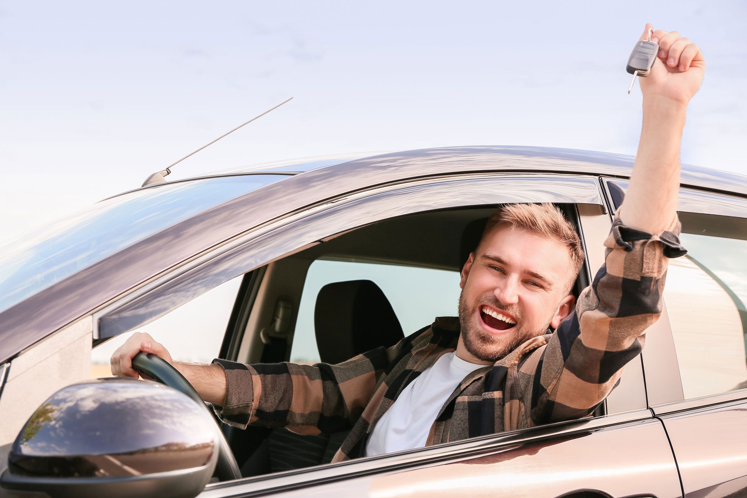 Mann streckt seinen Autoschlüssel in die Luft